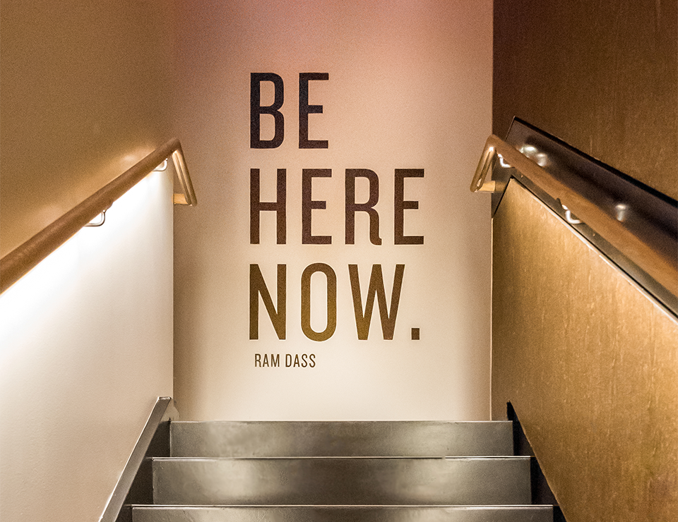 BInterior mural at Viva Day Spa + Med Spa with Ram Dass quote, "Be Here Now."